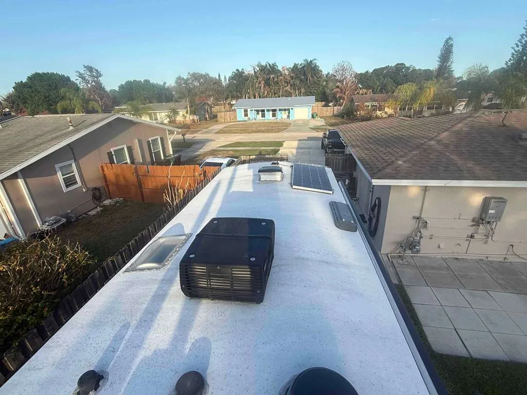 Roadwise RV technician replacing a rooftop AC unit on an RV at a Florida campground